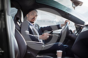 African man driving car and using modern smartphone