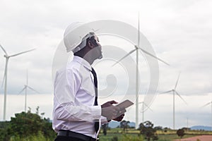 African man engineer holding laptop tablet with wind turbine