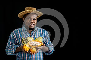 African man famer holding and showing many fresh cocoa On black background