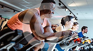 African man and friends on fitness bike in gym