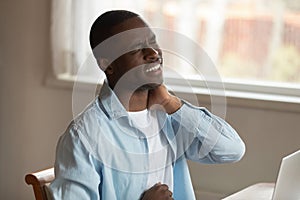 African man frowning massaging pinched nerve feels pain in neck