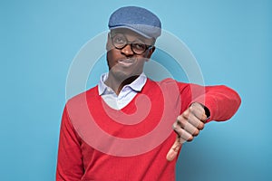 African man giving thumbs down gesture, looking with negative facial expression