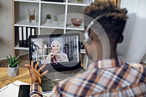 African man having video chat on laptop with muslim woman