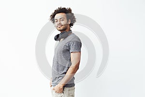 African man with headphones smiling looking at camera over white background. Copy space.