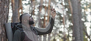 African man hiker looking for mobile network in forest