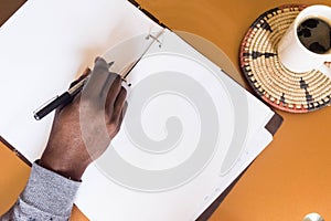 African man holding pen in hand to write on blank white paper