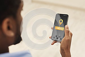 African man holding smartphone with opened taxi services mobile app on screen