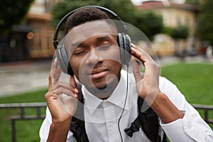 African man listening music in headphones with closed eyes and dreaming.