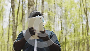 An african man with medical mask using the tablet in the forest. wireless or future technology concept