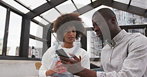 African man and mixed race woman using smartphone