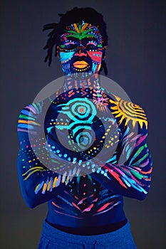 African man painted in fluorescent paint on face and muscular shirtless torso