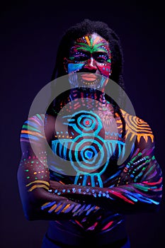 African man painted in fluorescent paint on face and muscular shirtless torso