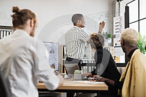 African man pointing on glass board with various graphs and charts.