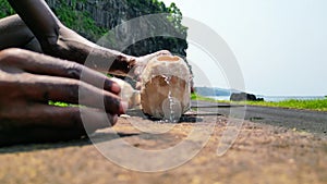 African man pouring coocnut water on the sandy beach in Sao Tome, Africe