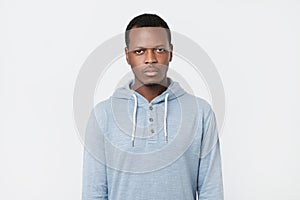 African man with serious expression looking at camera while posing against white studio wall.