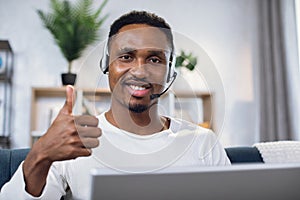 African man showing thumb up while working on laptop
