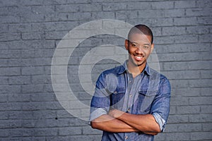 African man smiling against gray wall with blue shirt