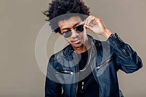 African man in sunglasses holding hand on glasses and looking away