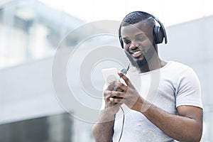 African man textmessaging on cellphone and listening to music