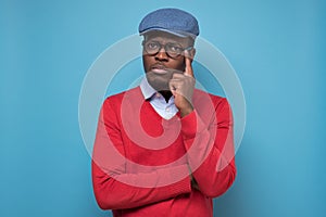 African man touching his chin, looking thoughtful and skeptical about something