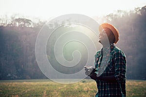 African man traveller holding film camera on a green meadow