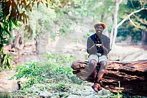 African man traveller sitting on the old tree