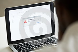 African man using laptop with application failure message on scr