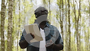 An african man using the tablet in the forest. wireless or future technology concept