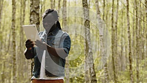 An african man using the tablet in the forest. wireless or future technology concept