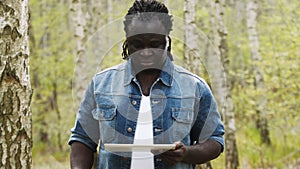 An african man using the tablet in the forest. wireless or future technology concept.