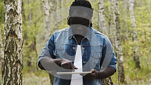 An african man using the tablet in the forest. wireless or future technology concept.