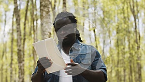 An african man using the tablet in the forest. wireless or future technology concept