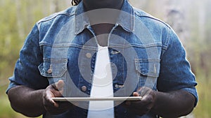 An african man using the tablet in the forest. wireless or future technology concept.