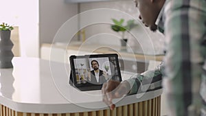 African man using tablet for video call with his partner, giving recommendations
