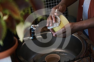 African man washing some dishes in his kitchen sink