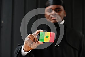 African man wear black durag hold Senegal flag at hand isolated dark background photo