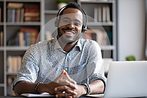 African man wear headset sit at desk looking at camera