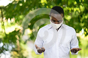 African man wear white shirt and face mask for virus protection with text Pray for the World corona virus covid-19 on green nature