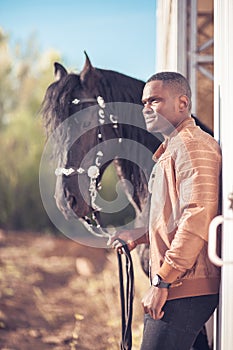 African Man wearing sunglasses near black horse in hangar