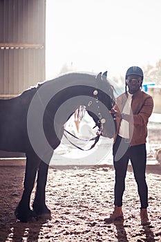 African Man wearing sunglasses near black horse in hangar