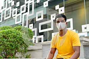 African man wearing yellow t-shirt and face mask outdoors in city