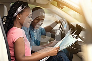 African man and woman in car looking at map