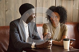 African man and woman talking flirting sitting at coffeehouse ta