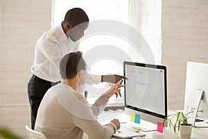 African mentor helping colleague with computer work explaining a