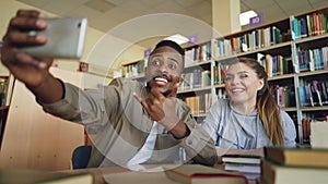 African merican guy and caucasian girl have fun smiling and taking selfie photos on smartphone camera at university