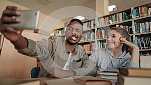 African merican guy and caucasian girl have fun smiling and taking selfie photos on smartphone camera at university