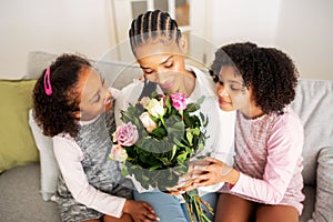 African Mommy Holding Flowers While Daughters Greeting Her At Home