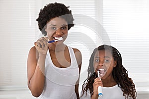 Mother And Daughter Brushing Their Teeth