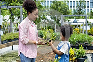African mother and daughter is choosing ornamental plant and blooming flower pot from the local garden center nursery during