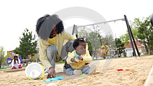 African mother and daughter playing with toys in the sand